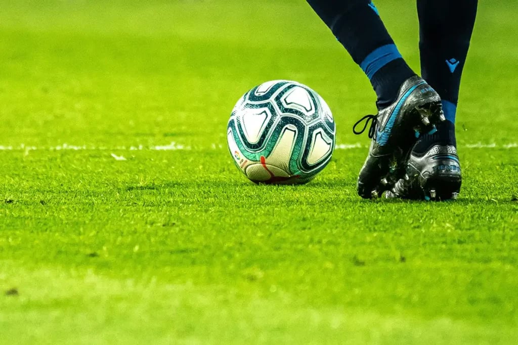 a soccer player's legs with a ball by there feet standing on grass