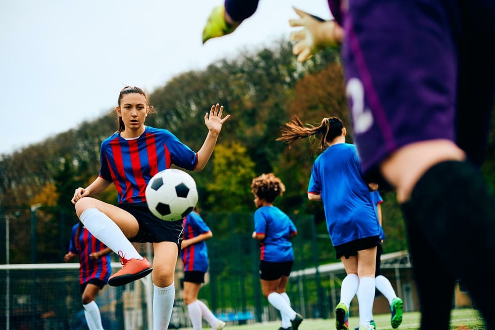 Female soccer player and goalkeeper exercising with the ball at the stadium.