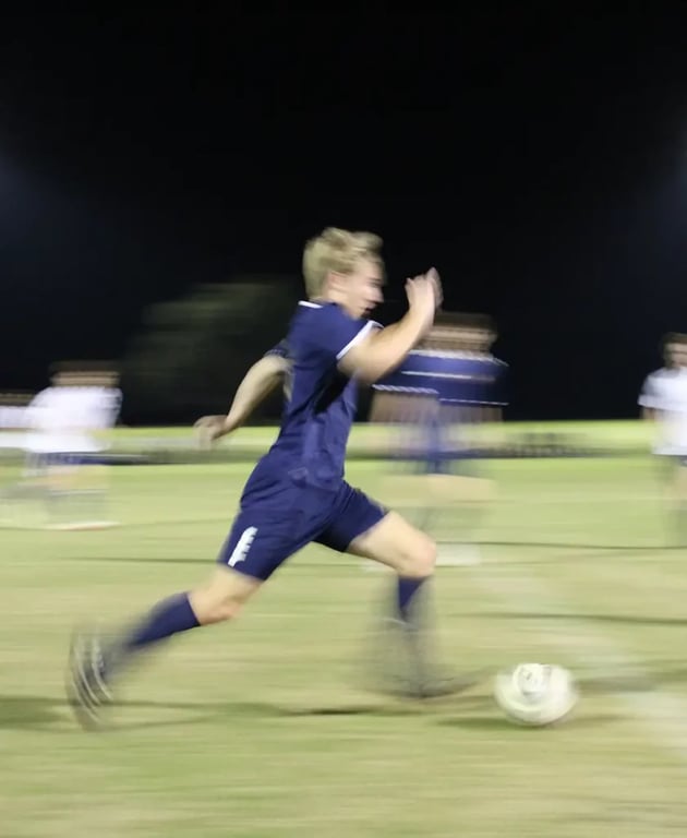 a-young-man-kicking-a-soccer-ball-on-top-of-a-field