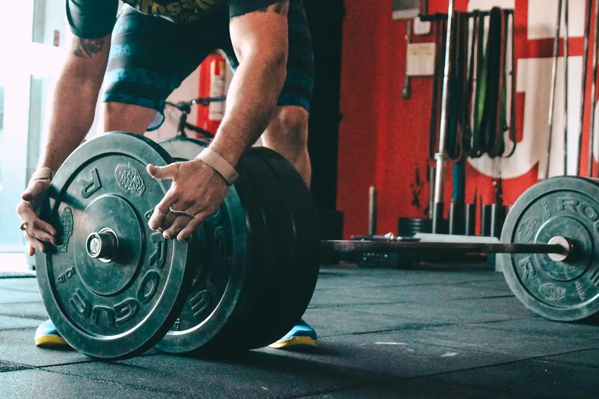 the hands of a weightlifter putting weights on a bar