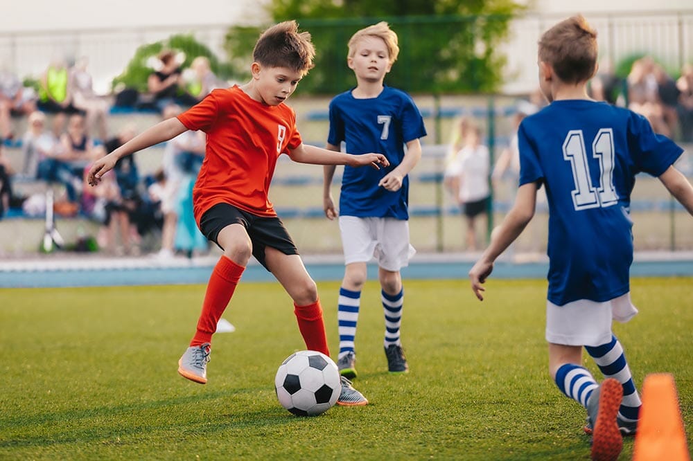 Young boys playing soccer game. Training and football match between youth soccer teams. Junior competition between players running and kicking soccer ball. Final game of football tournament for kids