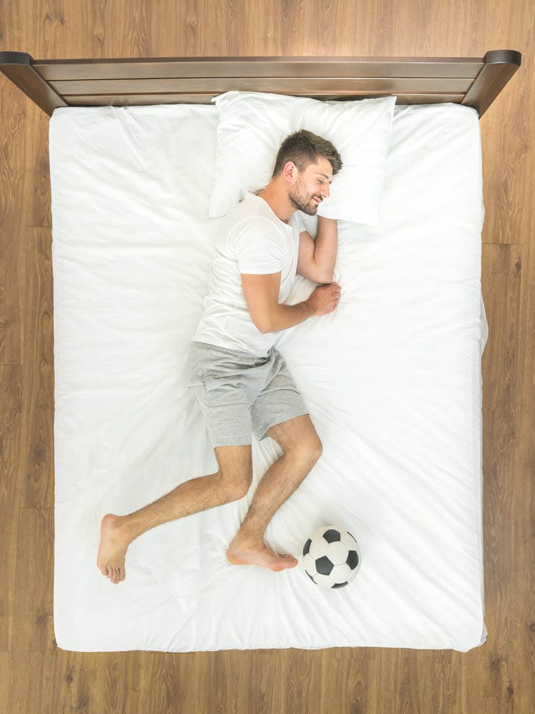 The man with a ball sleeping on the bed. view from above