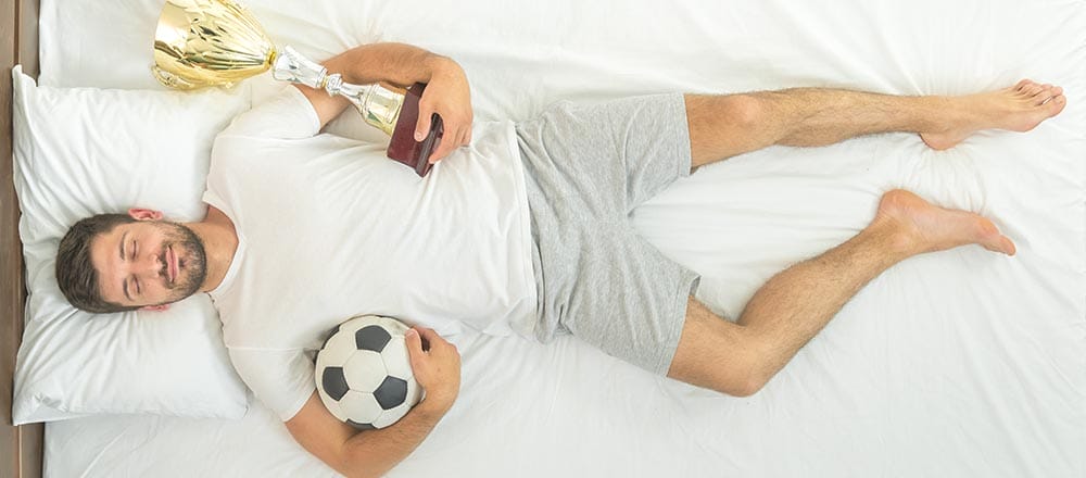 The man with a cup and a ball sleeping in the bed. view from above