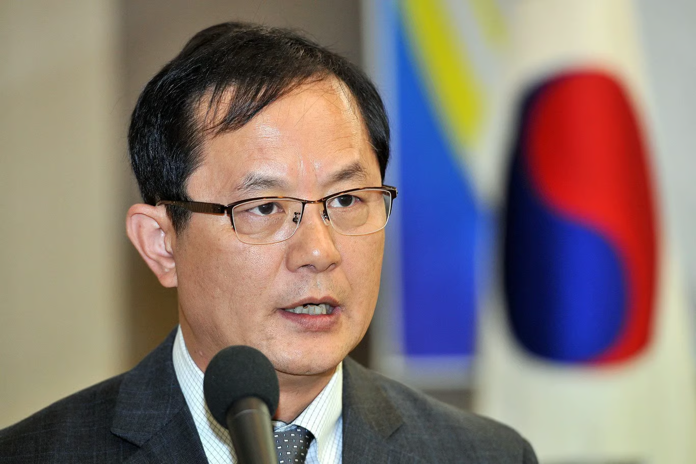 Kim Heung-kwang, former North Korean computer science professor, speaking at a microphone in front of a South Korean flag after his 2004 defection.