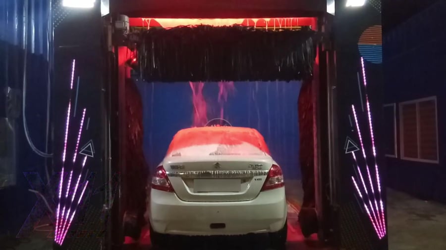 Water arcing over a saloon car from the arch inside a KKE X1.1 at night, the beam above it lit red and the RGB column arrays blazing either side