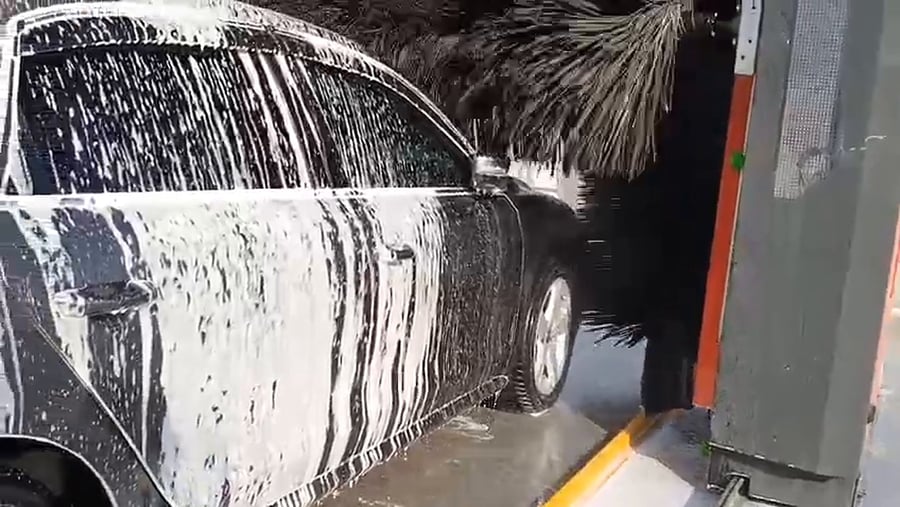 A vertical brush of a KKE X1.1 working down the side of a foam-covered saloon, the foam sheeting off the door and the wheel turning below