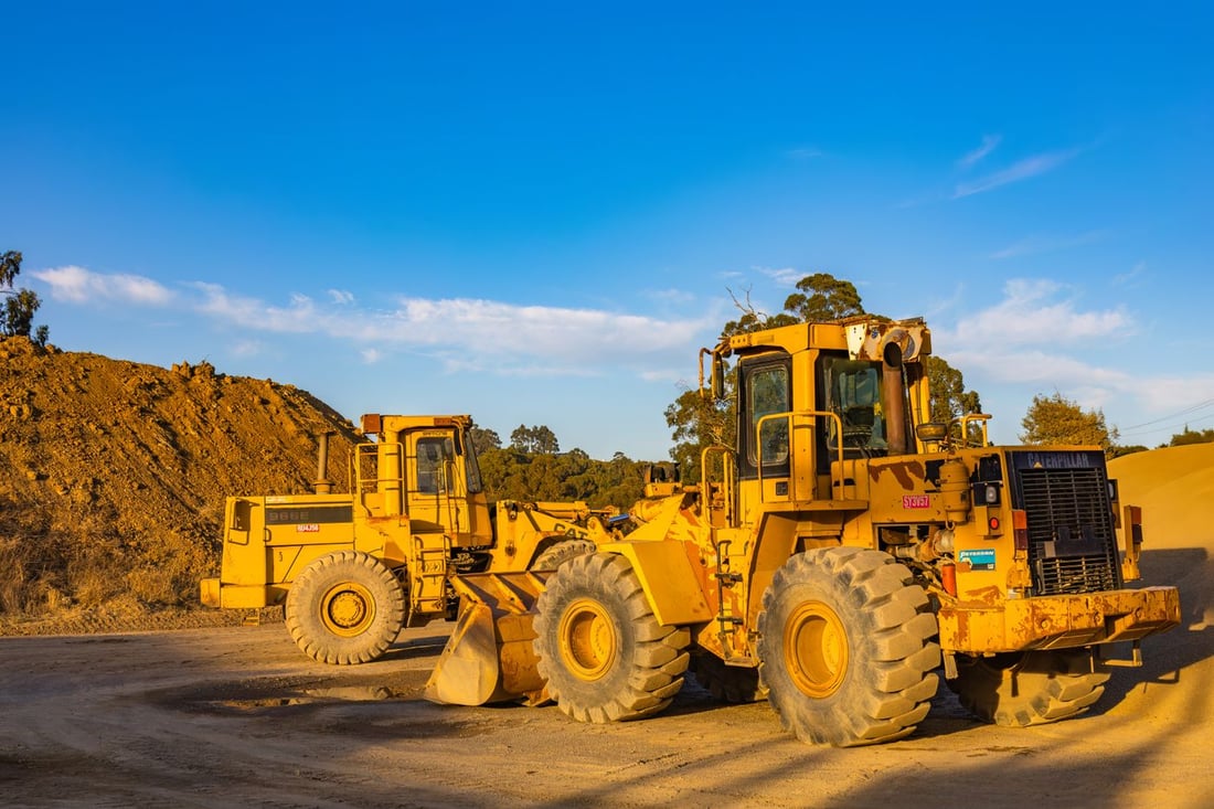 Two dust-covered wheel loaders parked in a site yard — typical medium-duty wash-rack equipment