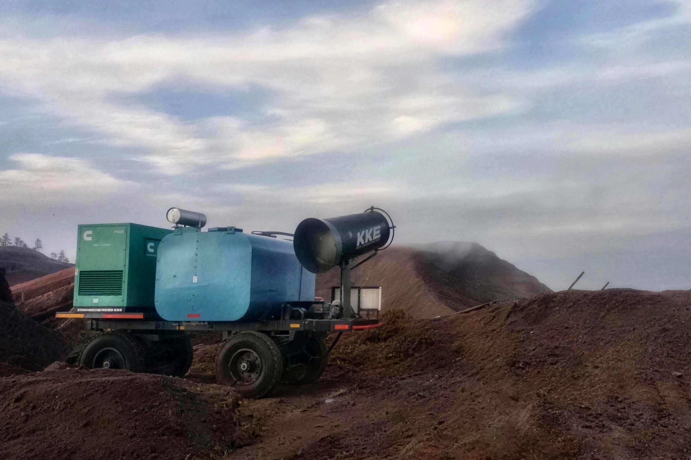 A KKE MistBeam fog cannon on a four-wheel towable trolley with an onboard water tank and a diesel generator, parked on a mining bench