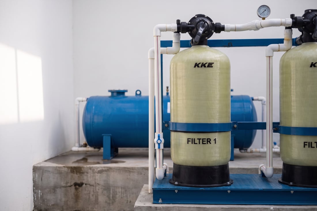 KKE W100 multimedia filter vessels installed on a skid frame, with multiport valves, PVC plumbing and storage tanks behind