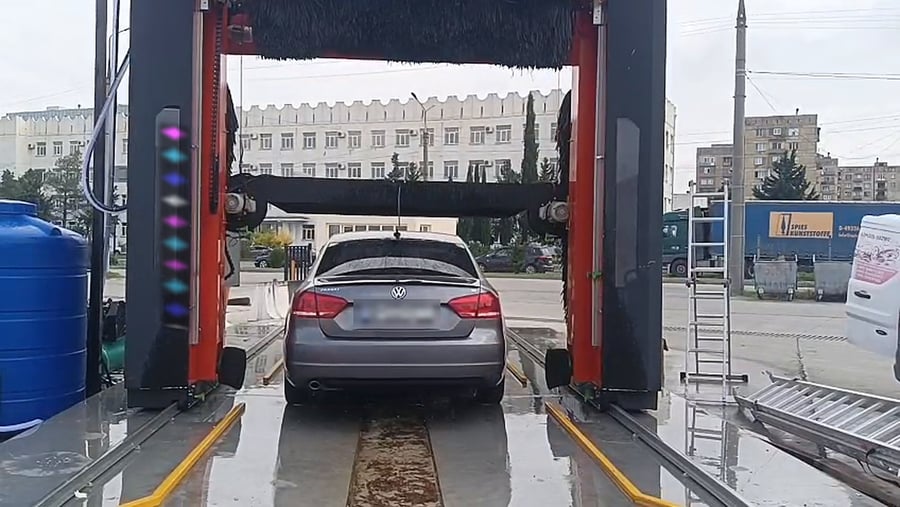 The blower bar of a KKE X1.1 down across the back of a saloon at the end of its wash, the brushes parked above it and the forecourt beyond