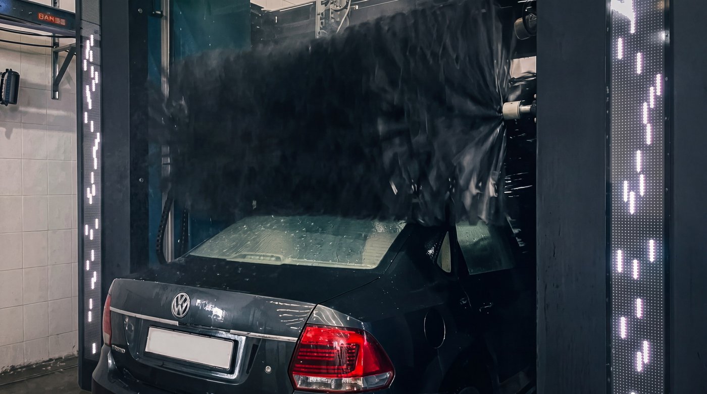 The roof brush working across the rear screen of a dark saloon inside the portal