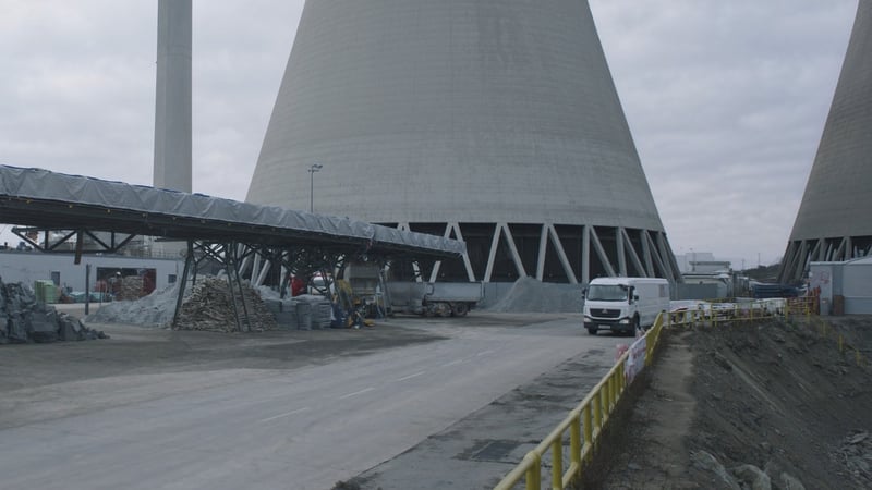 A power station ash handling yard, cooling towers behind a covered conveyor