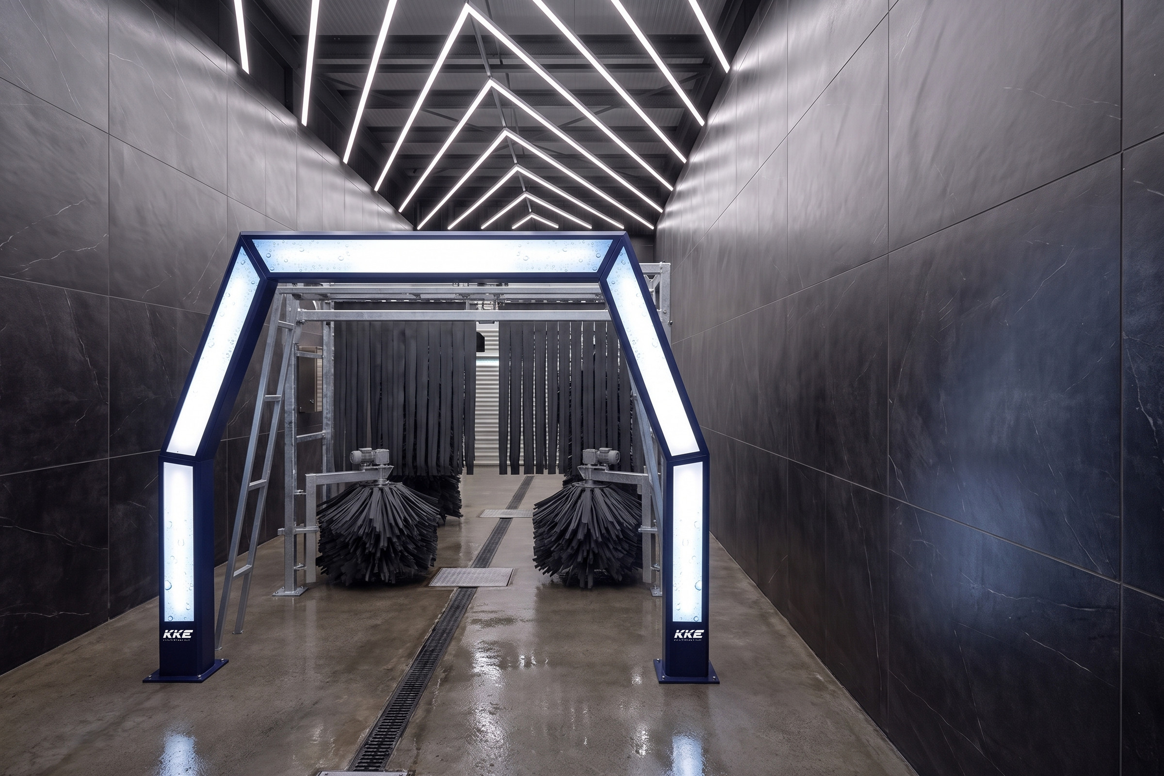 A KKE Z10 fleet car wash seen down the lane of a black-tiled wash bay: a navy entry portal with backlit white panels down each leg and across its header, two low charcoal skirt brush drums on the wet floor either side of a covered conveyor slot, and ranks of dark hanging curtain strips running away into the tunnel