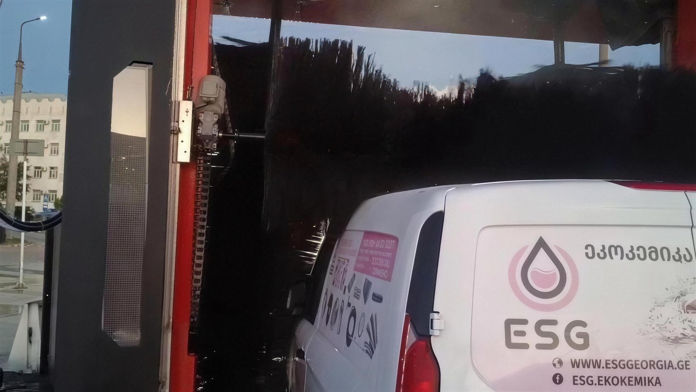 The vertical brush of a KKE X1.1 working down the flank of a white panel van, the van's roofline clear beneath the raised horizontal brush