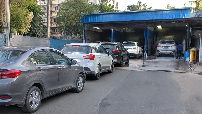 A car wash shop front on an Indian city street with cars waiting