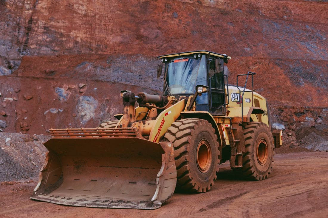 A mud-caked wheel loader on a quarry haul road — the class of machine a portable wash rack is built to clean