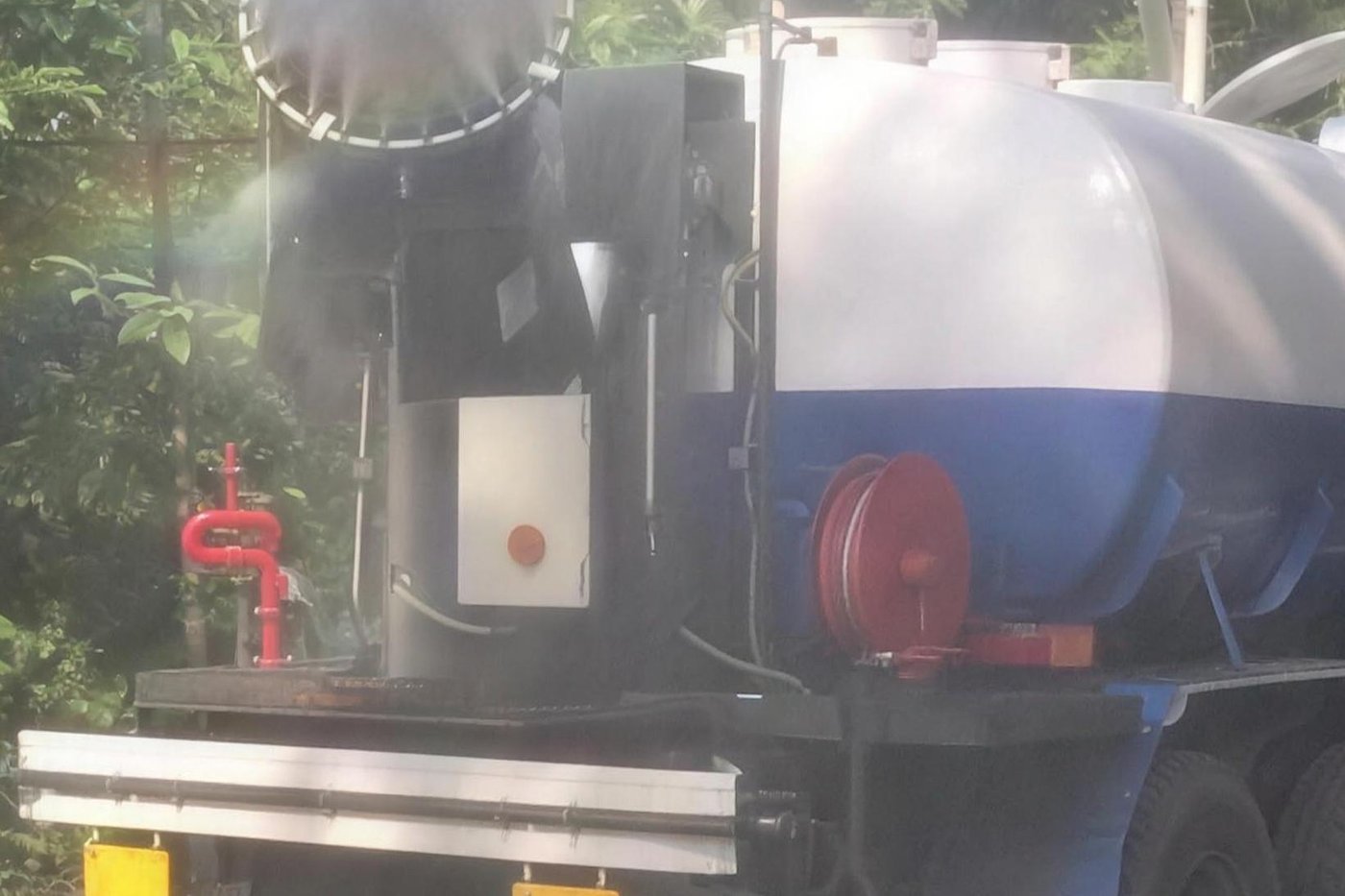 Close view of a truck-mounted MistBeam deck showing the slewing fog cannon, a red water monitor standpipe, a red hose reel and the control box