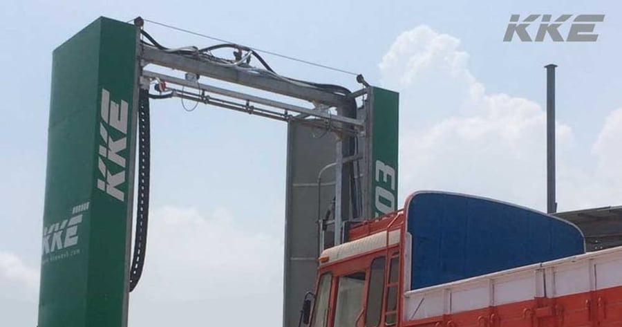 A KKE 503 in service: the green gantry on its rails with the stainless top nozzle beam, its hydraulic hoses and energy chain overhead, and a flatbed truck standing in the bay beneath it