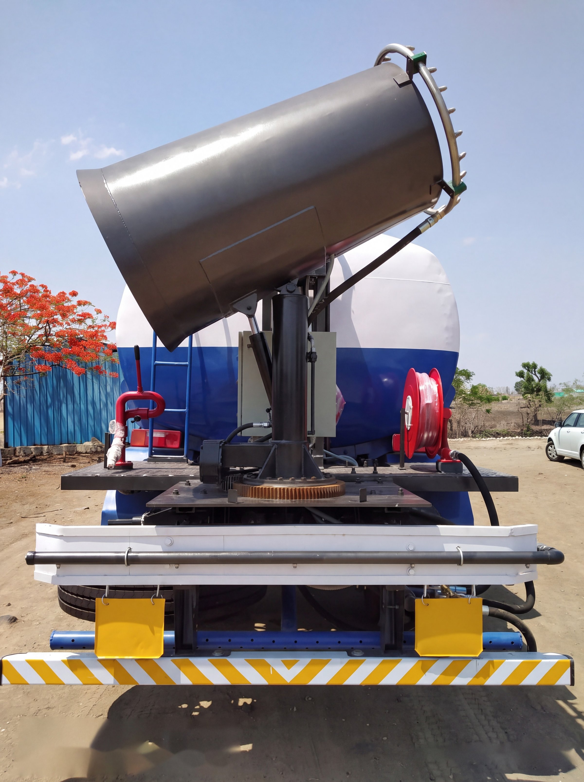 Rear elevation of a truck-mounted KKE MistBeam: the fog cannon on its slew ring, a red water monitor standpipe, a red hose reel and the road-wash spray manifold across the rear bumper