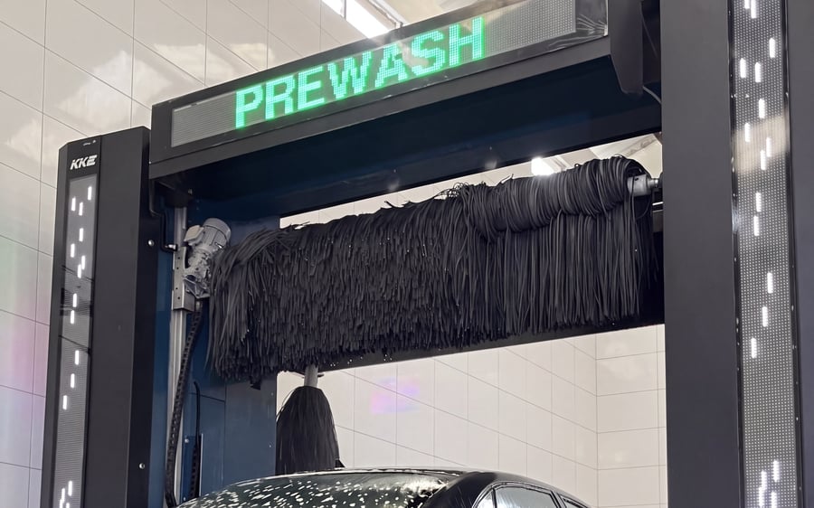 The beam display of a KKE X2 reading PREWASH with the roof brush hanging level and parked clear above the car's roofline, nothing yet touching the paint