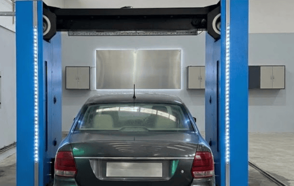 A car under the blower arch of a commissioned KKE ArrowClean bay, the LED columns lit on either side