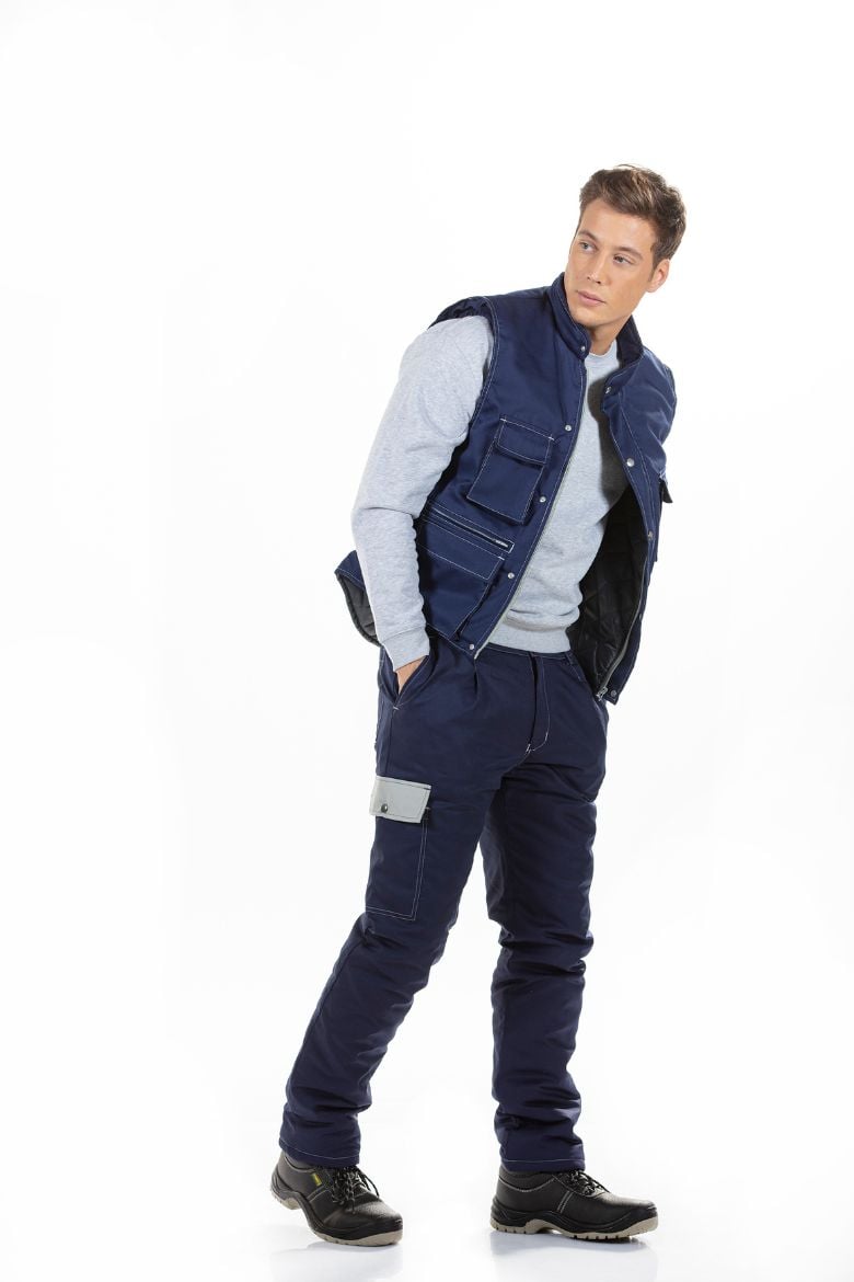 Homem vestido com uma calça acolchoada de cor azul com bolso lateral na perna de cor cinza para ser usada como roupa de trabalho