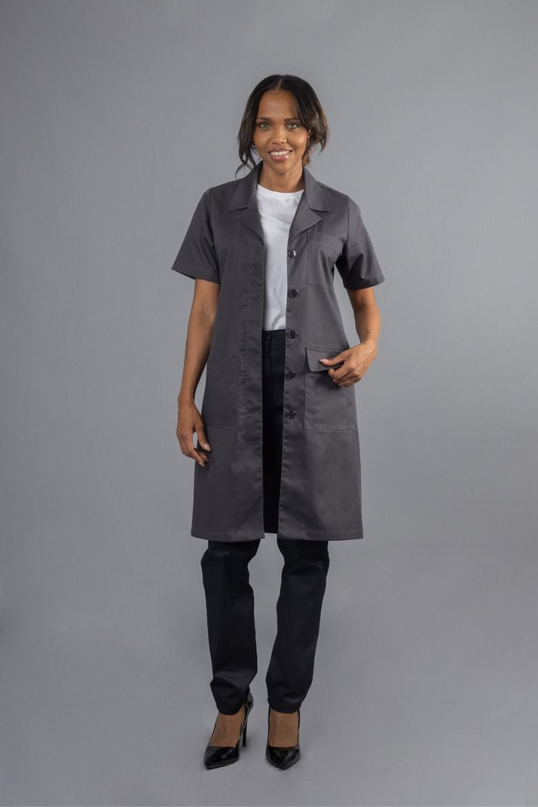 A lady dressed in black trousers and a Grey Short Sleeved Gown for Ladies, designed as a workwear garment manufactured by Unifardas.