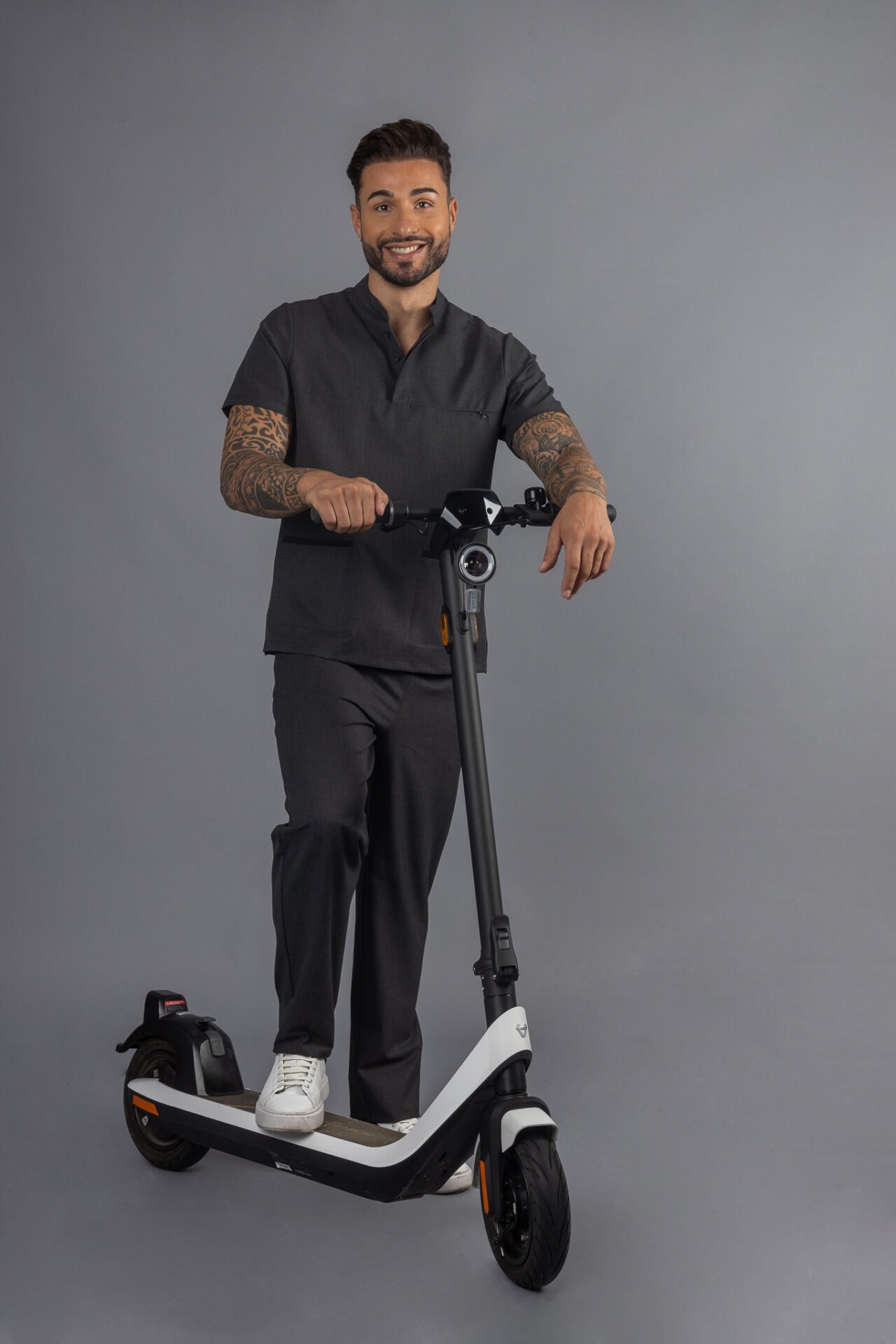 Health professional riding a scooter wearing a gray tunic and Men's Trousers with Belt Loop for a work uniform manufactured by unifardas