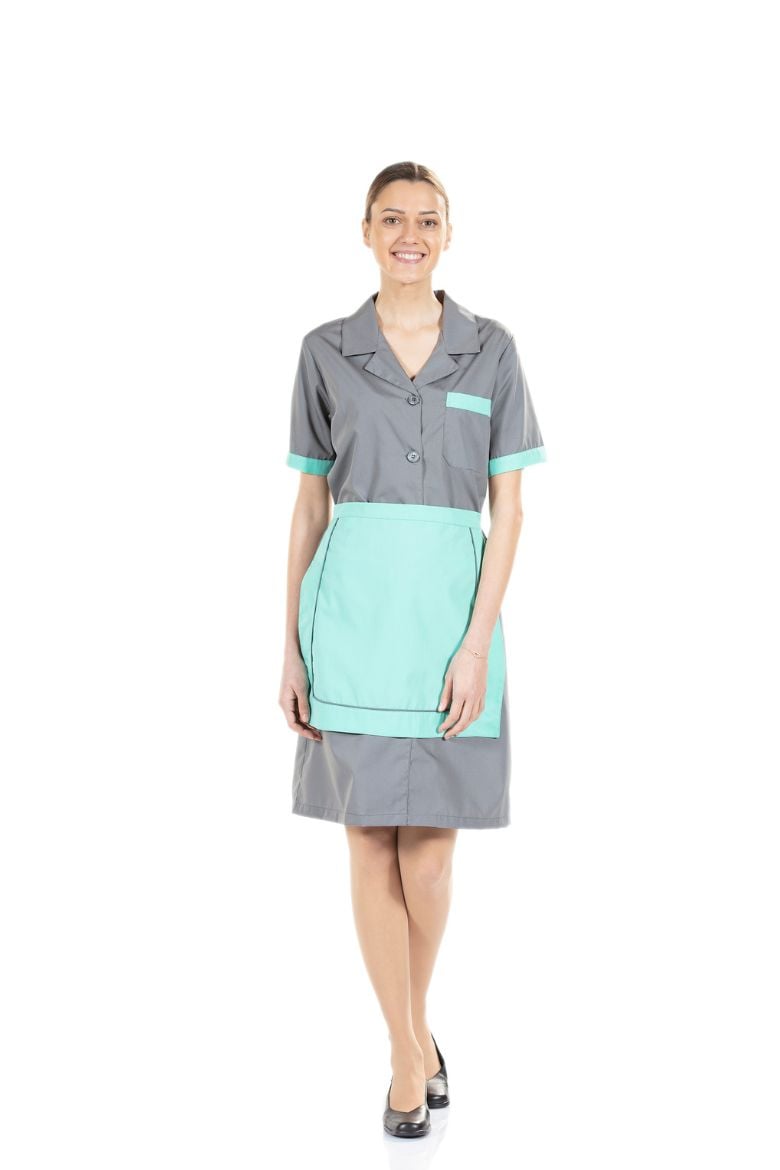 Senhora vestida com uma bata cinzenta e um avental de cintura de cor verde para ser usado como Uniforme Profissional para a área da Hotelaria e Restauração