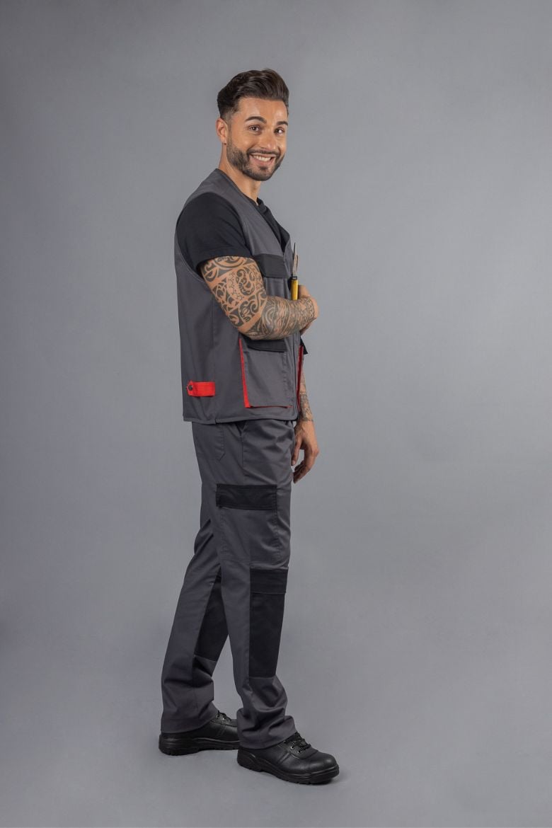 Trabalhador vestido com umas calças multibolsos de cor cinzenta e um colete para construção civil fabricado pela Unifardas