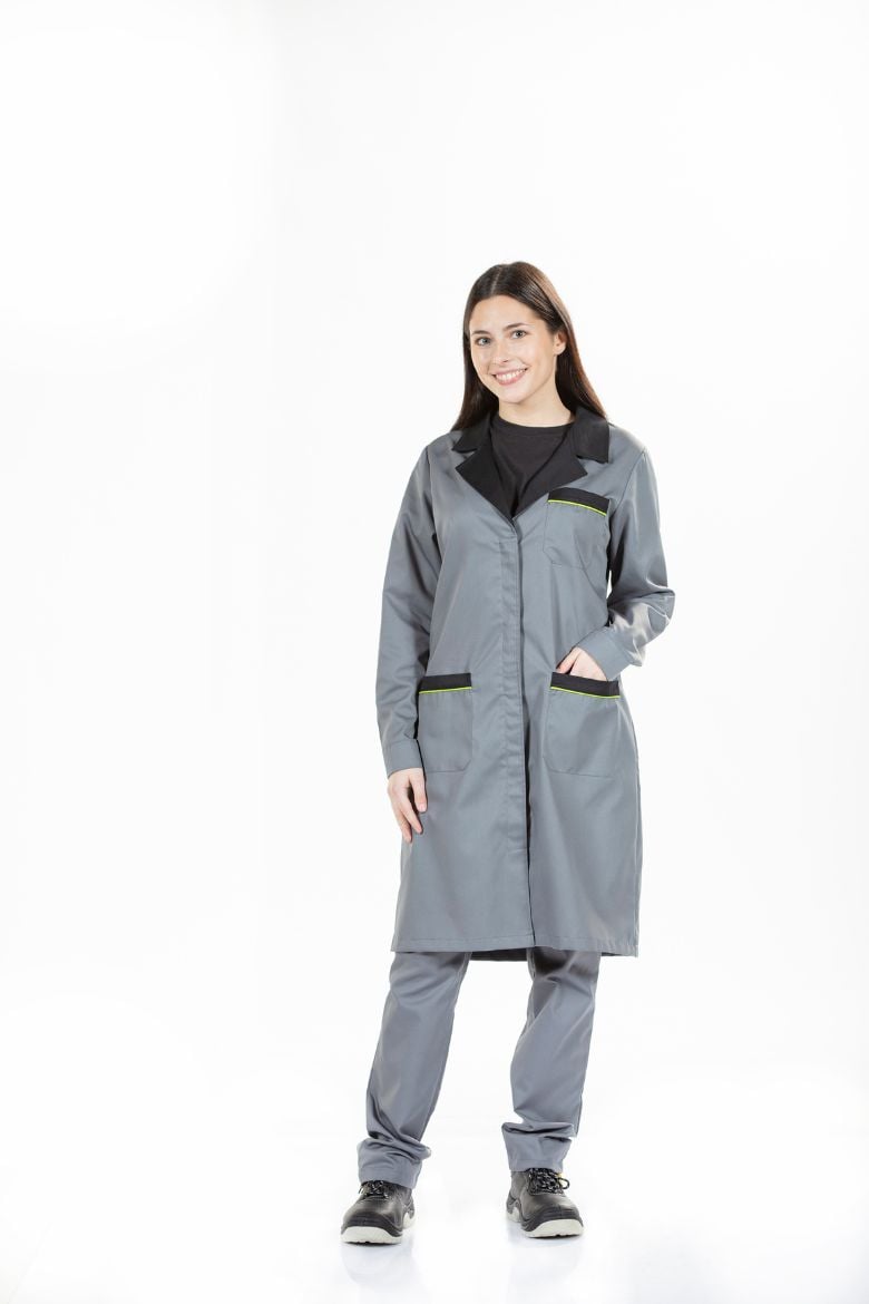 A worker wearing a Women's Industrial Coat in gray with black and green contrast details, manufactured by Unifardas