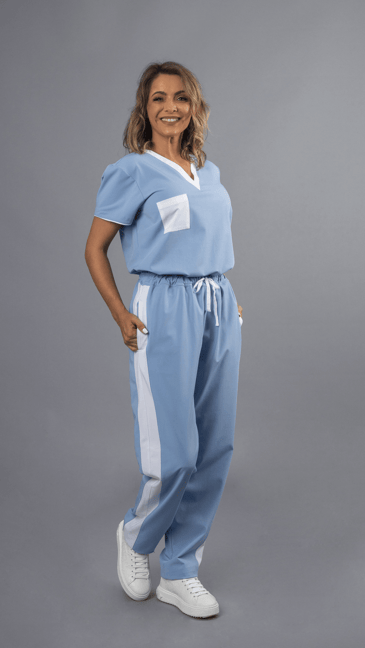 Trabalhadora da área da saúde vestida com uma túnica azul com contrastes a branco e uma calça azul com contraste branco para ser usada como farda profissional para a área da saúde