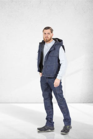 A man dressed in jeans and a denim work vest made by Unifardas to be worn as work clothes.