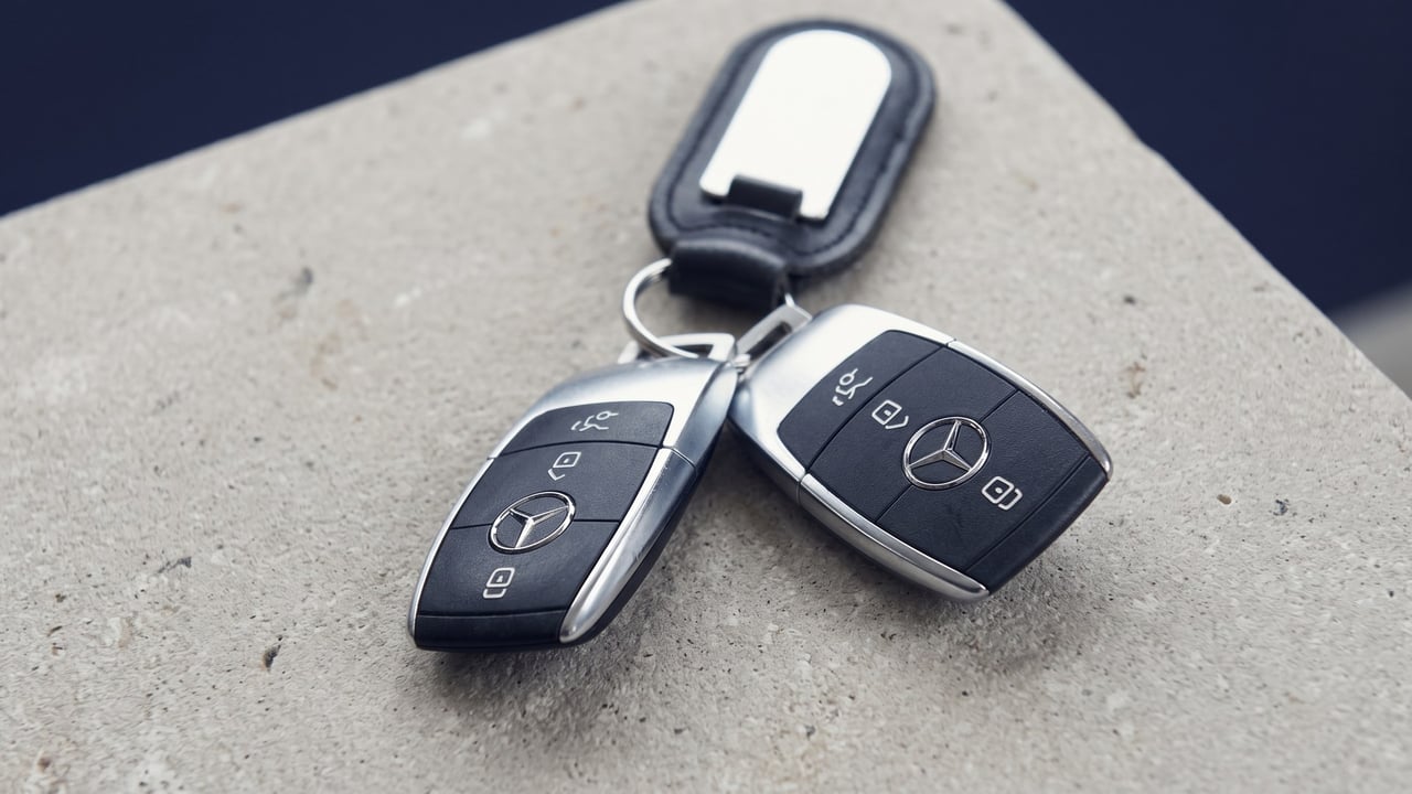 Two push-button car key fobs on a dark leather seat