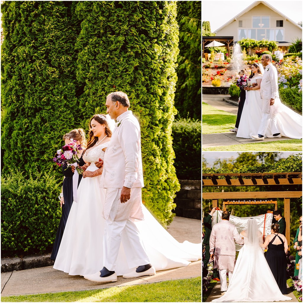 Wedding party walking outside: bride in white gown with bouquet, groom in light suit, joined by attendants beside tall evergreen hedge.