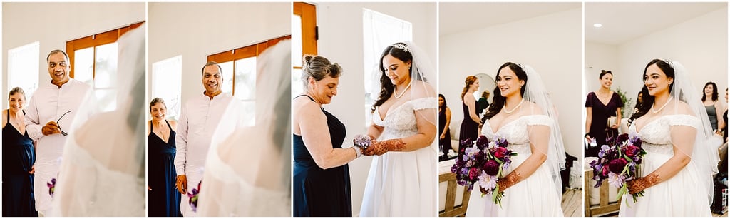 Bride in a white gown and veil stands with her parents and a bridesmaid in a sunlit room, preparing for the ceremony.