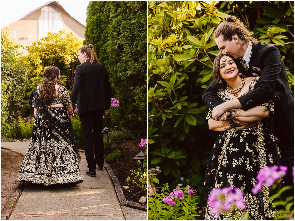 Couple walking hand in hand down a garden path, the woman in a black and gold embroidered gown far from the camera.