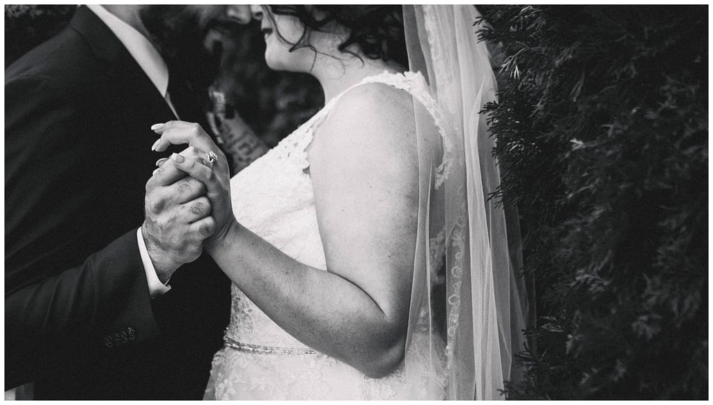 Premier Snohomish & Seattle Wedding Photographer | GSquared Weddings Photography Black-and-white photo of a bride and groom holding hands while dancing at their Snohomish wedding, with the bride in a lace dress and veil, and the groom wearing a suit. Their faces are partially visible and close together. 47.9129° N, 122.0982° W | Serving Snohomish, Seattle , Orlando & Beyond
