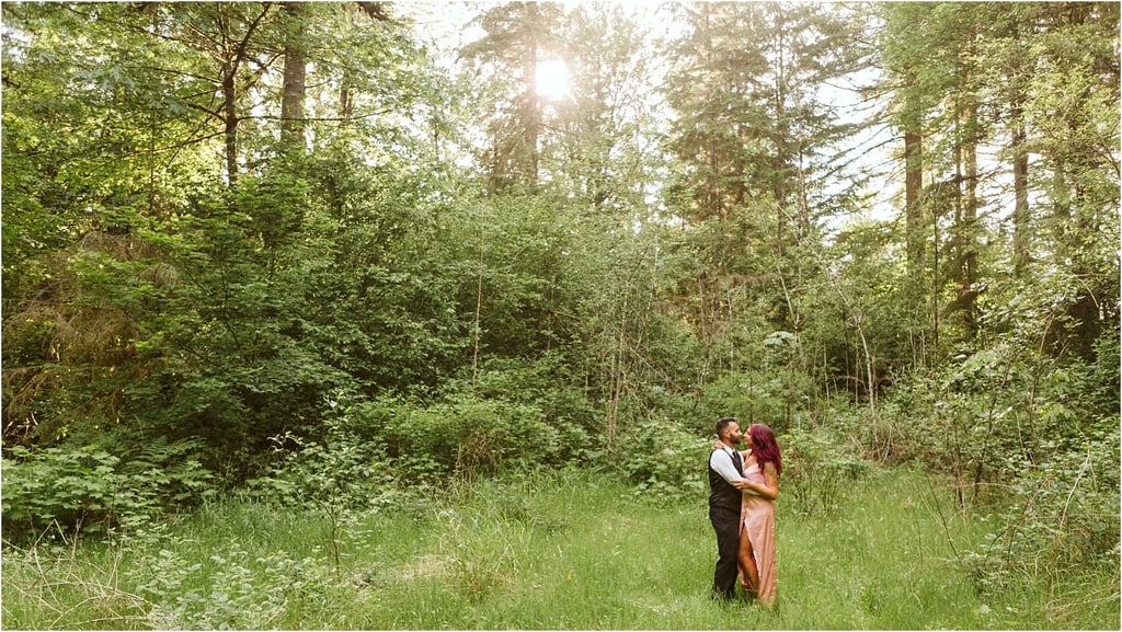 Premier Snohomish & Seattle Wedding Photographer | GSquared Weddings Photography A couple stands embracing in a sunlit forest clearing near Snohomish, surrounded by lush green trees and grass, with sunlight streaming through the branches—a perfect Seattle wedding engagement moment. 47.9129° N, 122.0982° W | Serving Snohomish, Seattle , Orlando & Beyond