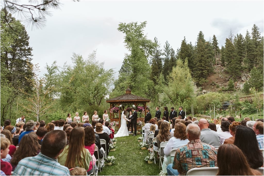 Premier Snohomish & Seattle Wedding Photographer | GSquared Weddings Photography A beautiful Snohomish wedding ceremony takes place outdoors in front of a gazebo surrounded by trees and mountains. Guests are seated on white chairs, and the wedding party stands on either side of the couple. 47.9129° N, 122.0982° W | Serving Snohomish, Seattle , Orlando & Beyond