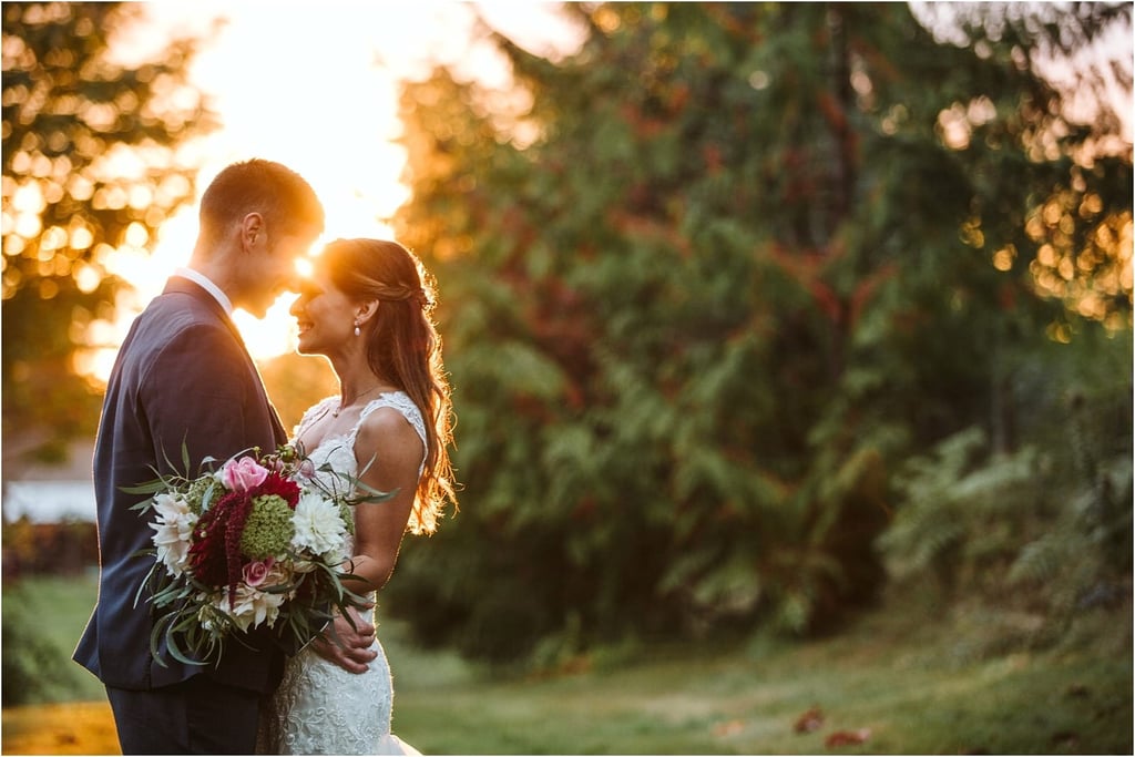 Premier Snohomish & Seattle Wedding Photographer | GSquared Weddings Photography A bride and groom stand close together outdoors at sunset, smiling and holding a bouquet of flowers, with soft sunlight filtering through trees in the background—a perfect Snohomish Seattle wedding moment. 47.9129° N, 122.0982° W | Serving Snohomish, Seattle , Orlando & Beyond