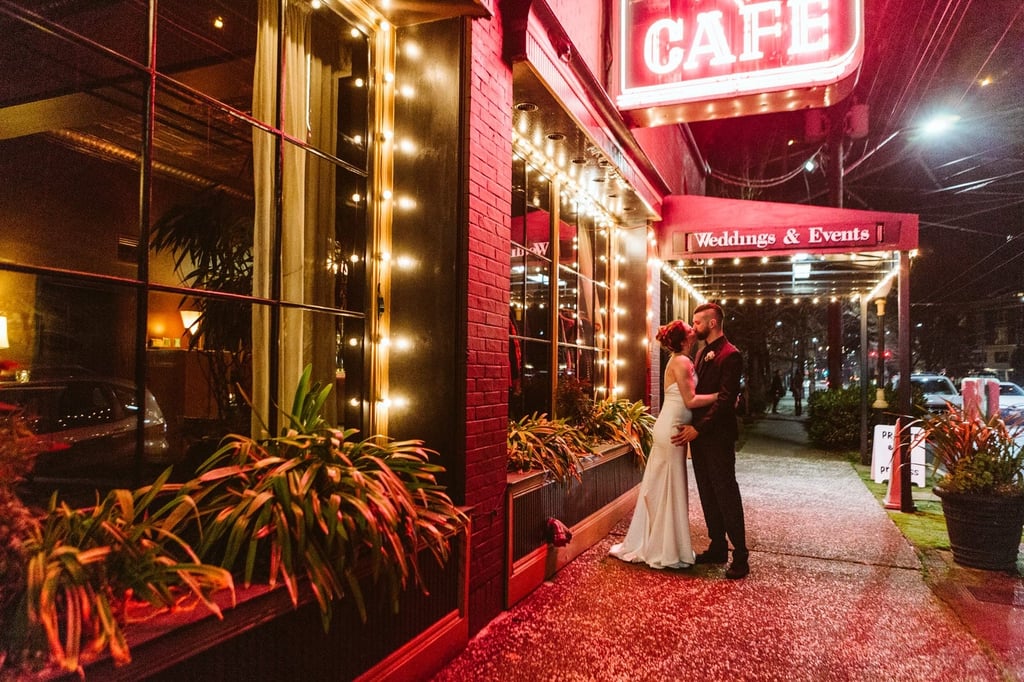 seattle wedding photographer at Lake union cafe at night under the sign bride and groom kissing