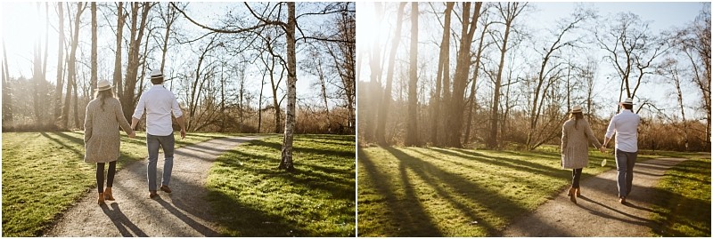 Premier Snohomish & Seattle Wedding Photographer | GSquared Weddings Photography Two people wearing hats and casual clothes walk hand-in-hand down a sunlit, tree-lined path in a park near Snohomish. The light casts long shadows and the trees are bare, evoking an early spring or late autumn Seattle engagement session. 47.9129° N, 122.0982° W | Serving Snohomish, Seattle , Orlando & Beyond