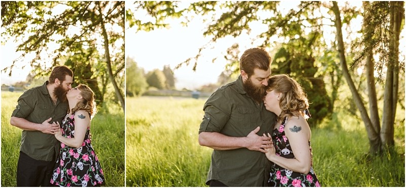 Premier Snohomish & Seattle Wedding Photographer | GSquared Weddings Photography A couple embraces in a sunlit green field near Snohomish, standing close under trees. The bearded man in a green shirt gently kisses the forehead of his tattooed partner, capturing a tender Seattle wedding engagement moment. 47.9129° N, 122.0982° W | Serving Snohomish, Seattle , Orlando & Beyond