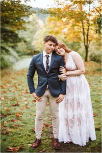 Premier Snohomish & Seattle Wedding Photographer | GSquared Weddings Photography A couple stands outdoors in a park with autumn leaves. The woman in a white lace dress rests her head on the man's shoulder—both calm and content during their Snohomish Seattle wedding engagement session. 47.9129° N, 122.0982° W | Serving Snohomish, Seattle , Orlando & Beyond