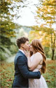 Premier Snohomish & Seattle Wedding Photographer | GSquared Weddings Photography A couple kisses outdoors in a lush, green landscape with autumn trees during their Snohomish engagement. The person on the left wears a dark suit, and the person on the right has long red hair and a light dress. 47.9129° N, 122.0982° W | Serving Snohomish, Seattle , Orlando & Beyond