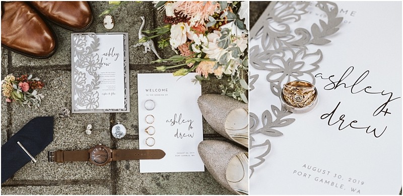 Premier Snohomish & Seattle Wedding Photographer | GSquared Weddings Photography A flat lay of wedding items on stone: invitation suite with floral cutouts, a Snohomish welcome card, wedding rings, wristwatch, boutonniere and pin, brown shoes, tan flats, a navy tie, and a bouquet—perfect for a Seattle wedding engagement. 47.9129° N, 122.0982° W | Serving Snohomish, Seattle , Orlando & Beyond