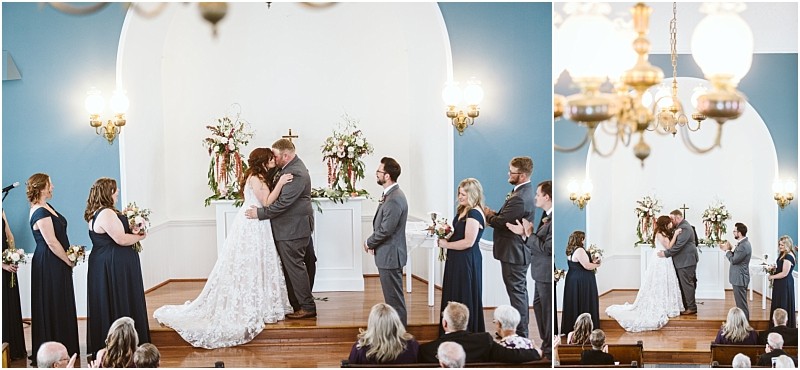 Premier Snohomish & Seattle Wedding Photographer | GSquared Weddings Photography A bride and groom kiss at the altar during a Snohomish wedding ceremony in a small chapel, surrounded by their navy blue-clad wedding party, as guests watch from the pews. 47.9129° N, 122.0982° W | Serving Snohomish, Seattle , Orlando & Beyond