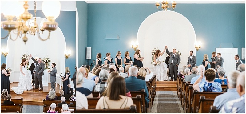 Premier Snohomish & Seattle Wedding Photographer | GSquared Weddings Photography A Snohomish wedding ceremony takes place in a bright, blue-walled chapel. The bride and groom stand at the altar with their wedding party, raising joined hands as guests watch from pews. 47.9129° N, 122.0982° W | Serving Snohomish, Seattle , Orlando & Beyond