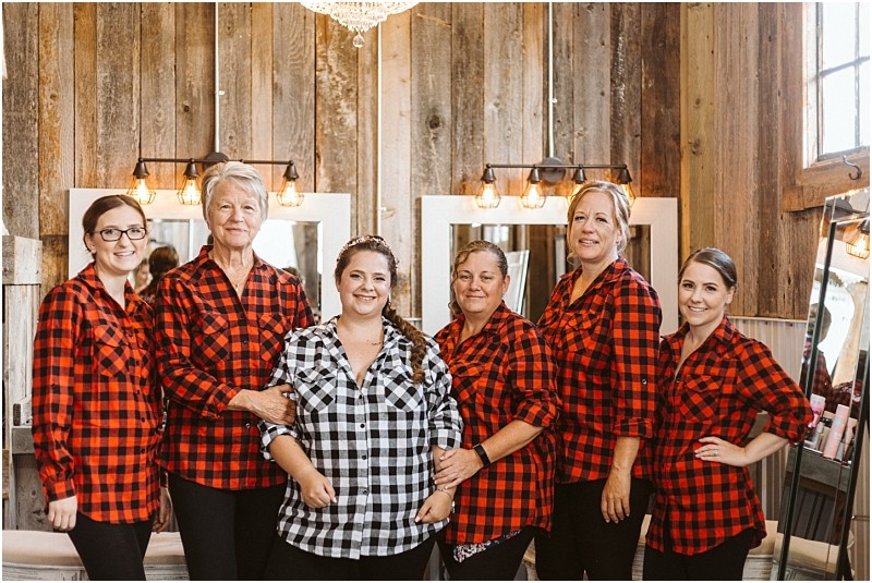 Premier Snohomish & Seattle Wedding Photographer | GSquared Weddings Photography Six women stand together smiling in a rustic, wood-paneled room near Seattle. Five wear matching red-and-black plaid shirts, while one in the center wears a black-and-white plaid shirt—capturing a joyful Snohomish wedding or engagement moment. 47.9129° N, 122.0982° W | Serving Snohomish, Seattle , Orlando & Beyond
